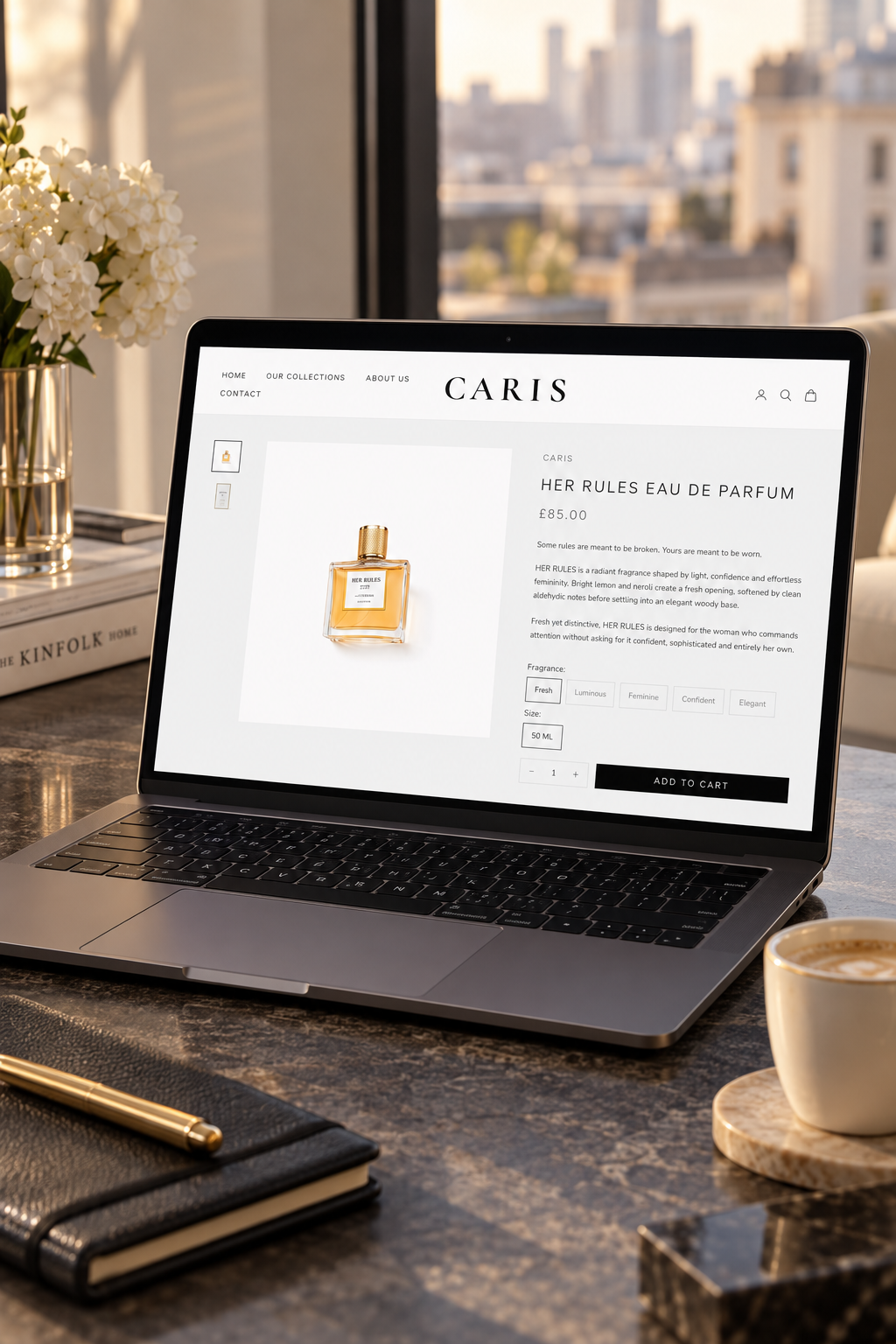 A laptop on a dark marble desk displaying a perfume product page on screen, styled with a cup of coffee, a notebook, and flowers in a bright modern room.
