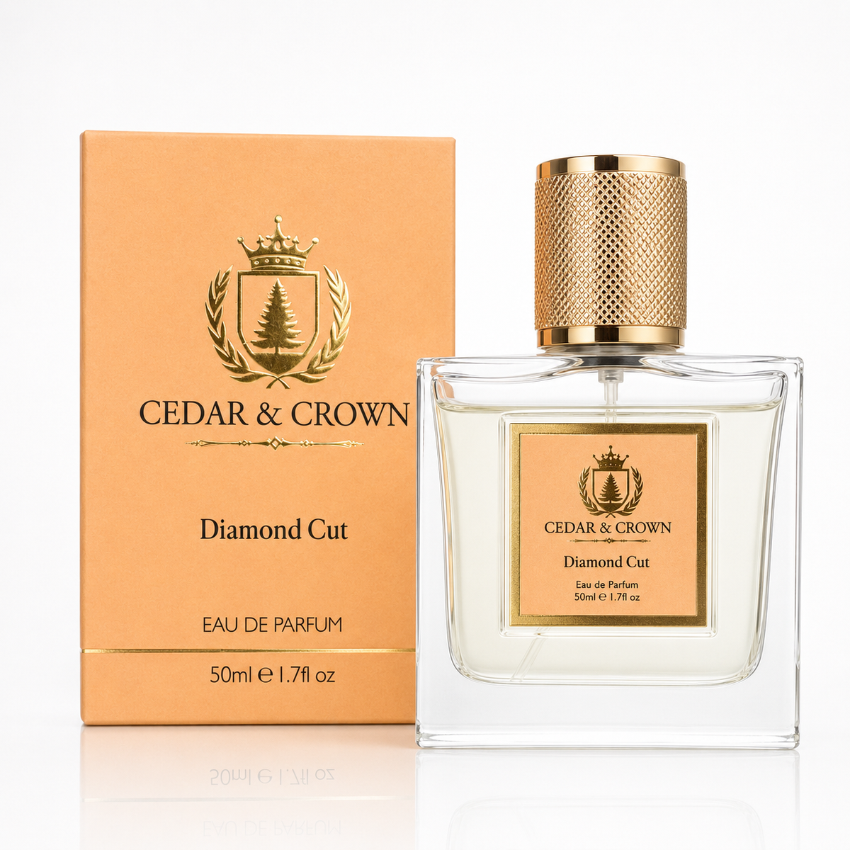 A bottle of Cedar & Crown Diamond Cut Eau de Parfum next to its matching peach-colored packaging box, both featuring a gold crest logo and set against a clean white background with a subtle reflection.