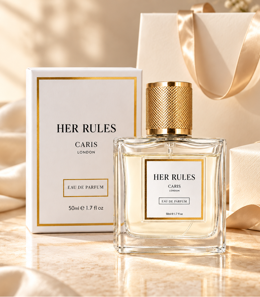 A bottle of HER RULES Paris Eau de Parfum with its white and gold box, styled on a marble surface with gift bags, ribbons, and baby's breath flowers.