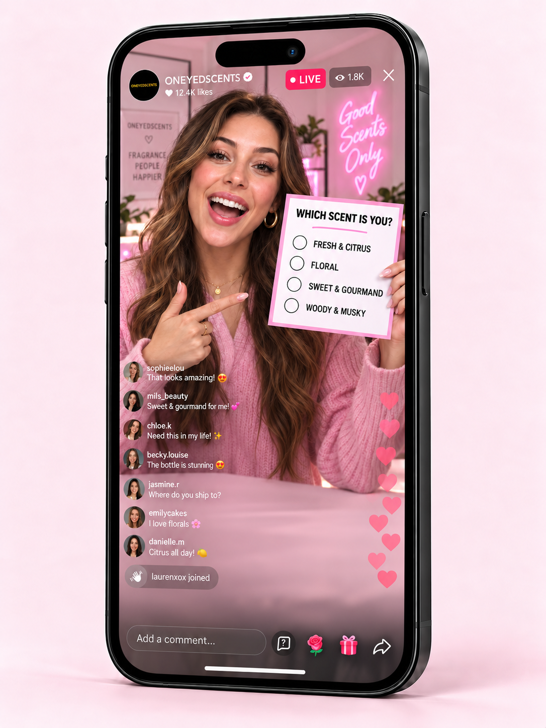 A black smartphone mockup displaying a pink-themed live streaming video screen with a woman holding a scent quiz card, set against a solid light pink background.